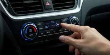 Mão ajustando o controle do ar-condicionado no painel de um carro, simbolizando o uso correto para economia.