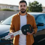 Pessoa segurando chave de carro com veículo ao fundo, simbolizando financiamento com FGTS.