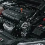 Mecânico inspecionando motor de carro para manutenção preventiva, fundamental para evitar desgaste prematuro.