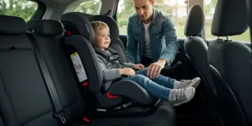 Pai ou mãe certificando-se de que a criança está segura na cadeirinha do carro, com cinto de segurança ajustado.