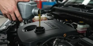 Mecânico realizando a troca de óleo em um motor de carro, com foco no óleo novo sendo adicionado.